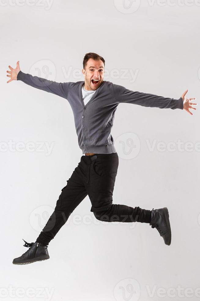 foto van vrolijk jong Mens gekleed in zwart t-shirt jumping over- wit achtergrond op zoek Bij camera.