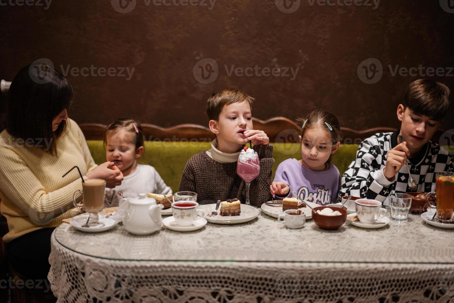 gelukkig familie aan het eten desserts samen Bij knus cafe en hebben plezier. jongen kind drinken melk schudden. foto
