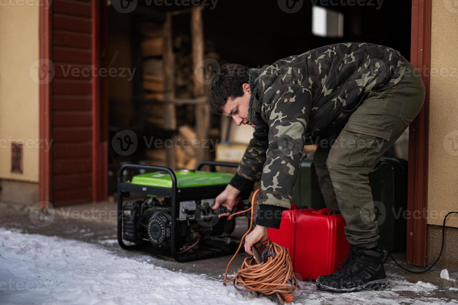 Mens slijtage in leger jasje met benzine portable mobiel backup standby generator. foto