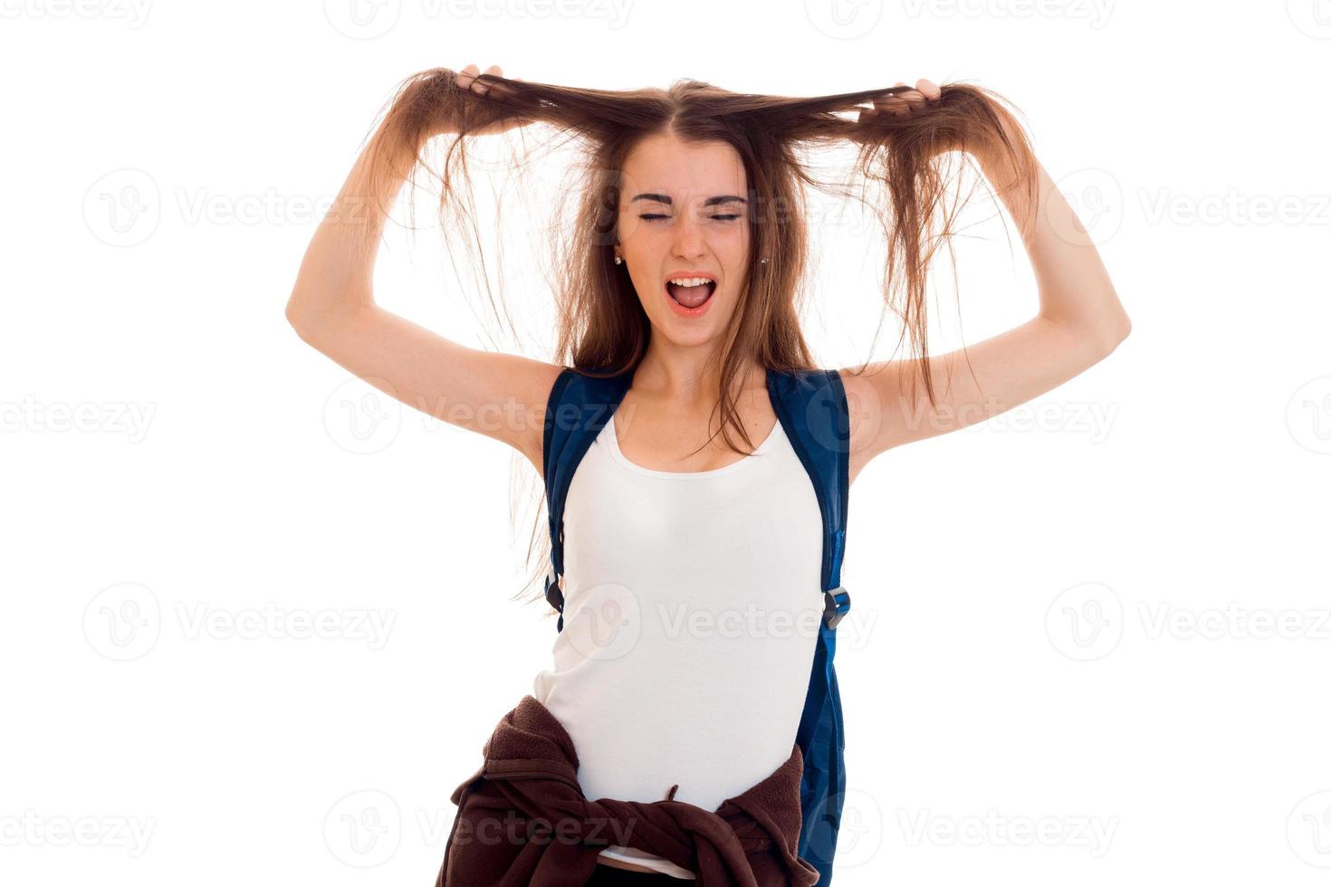 grappig jong brunette leerling met blauw rugzak Aan haar schouders poseren geïsoleerd Aan wit achtergrond foto