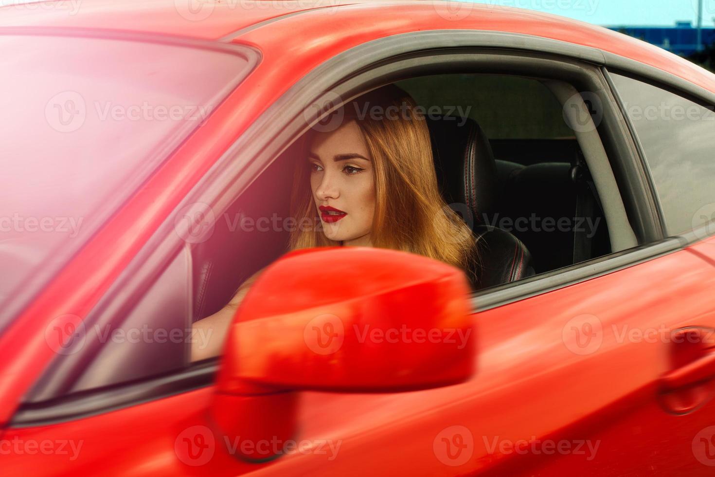 meisje met rood lippen het rijden een auto foto