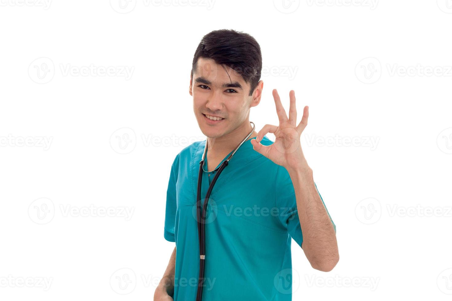 mooi hoor elegant dokter in blauw uniform met stethoscoop tonen OK geïsoleerd Aan wit achtergrond foto