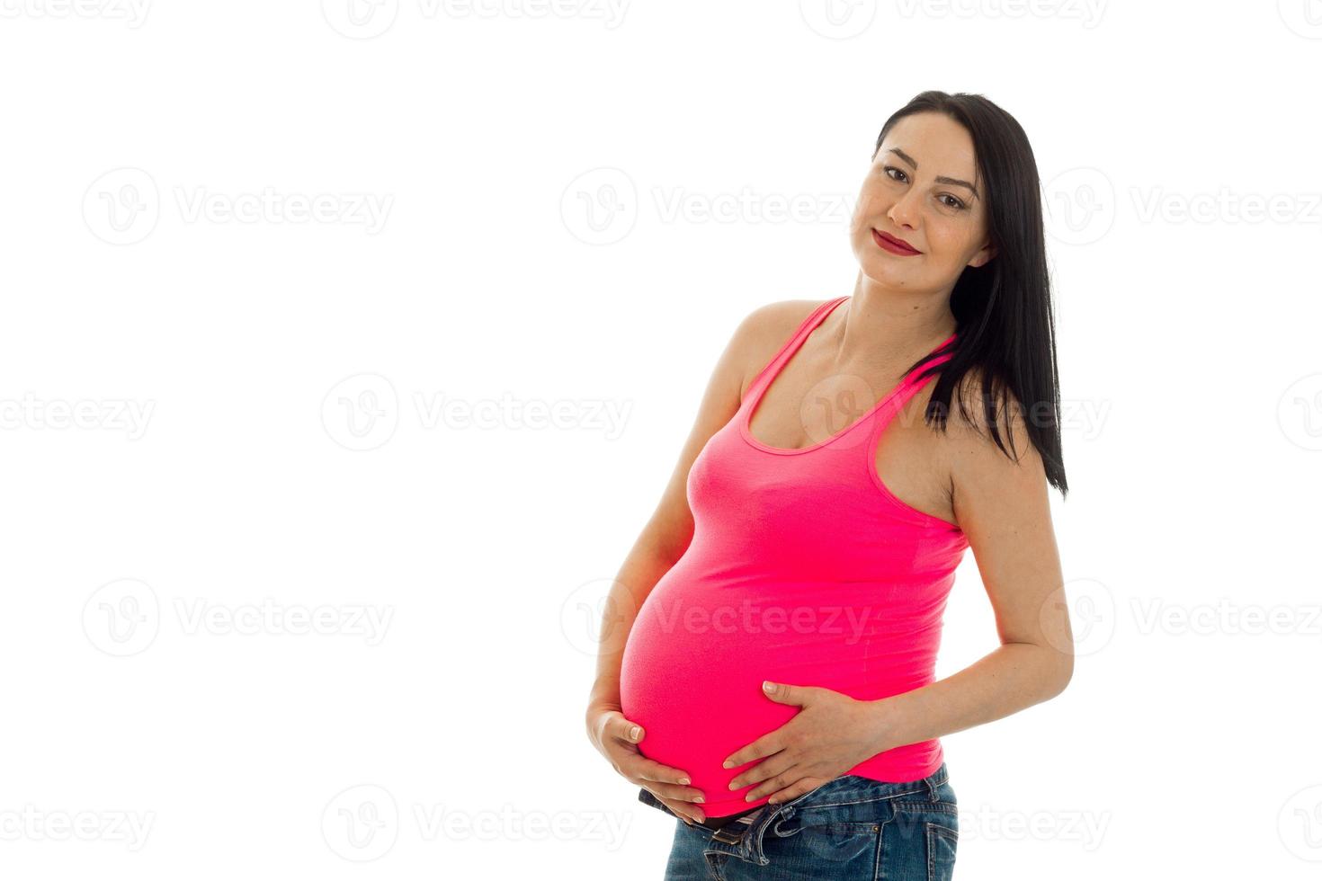 portret van jong schattig zwanger vrouw aanraken haar buik en poseren Aan camera geïsoleerd Aan wit achtergrond foto