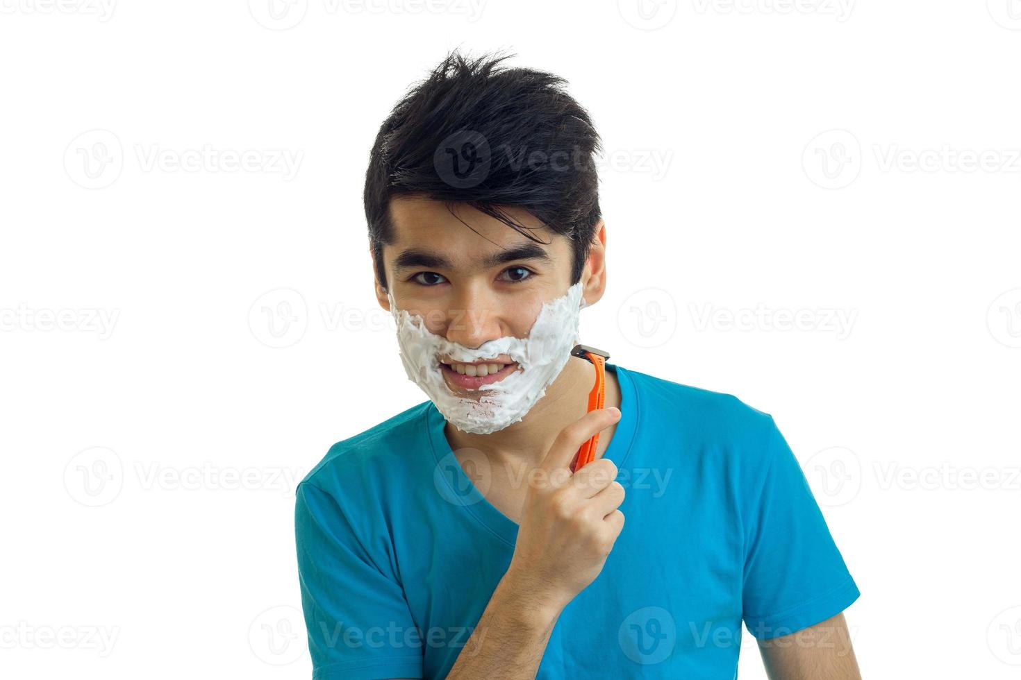 grappig knap jong vent looks in de camera met de schuim Aan uw gezicht en scheert zijn baard machine foto