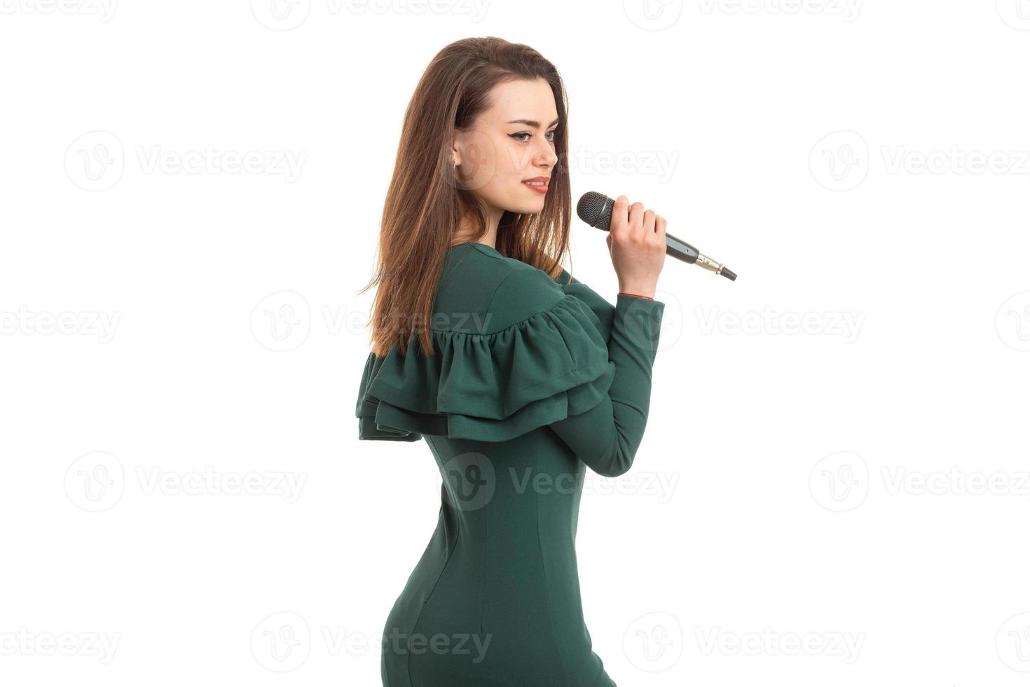 charmant meisje in een groen jurk zingt in een microfoon foto