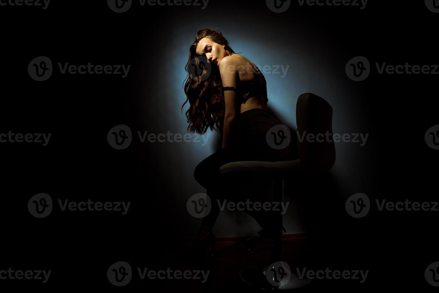 prachtig dame met gekruld kapsel in donker studio foto