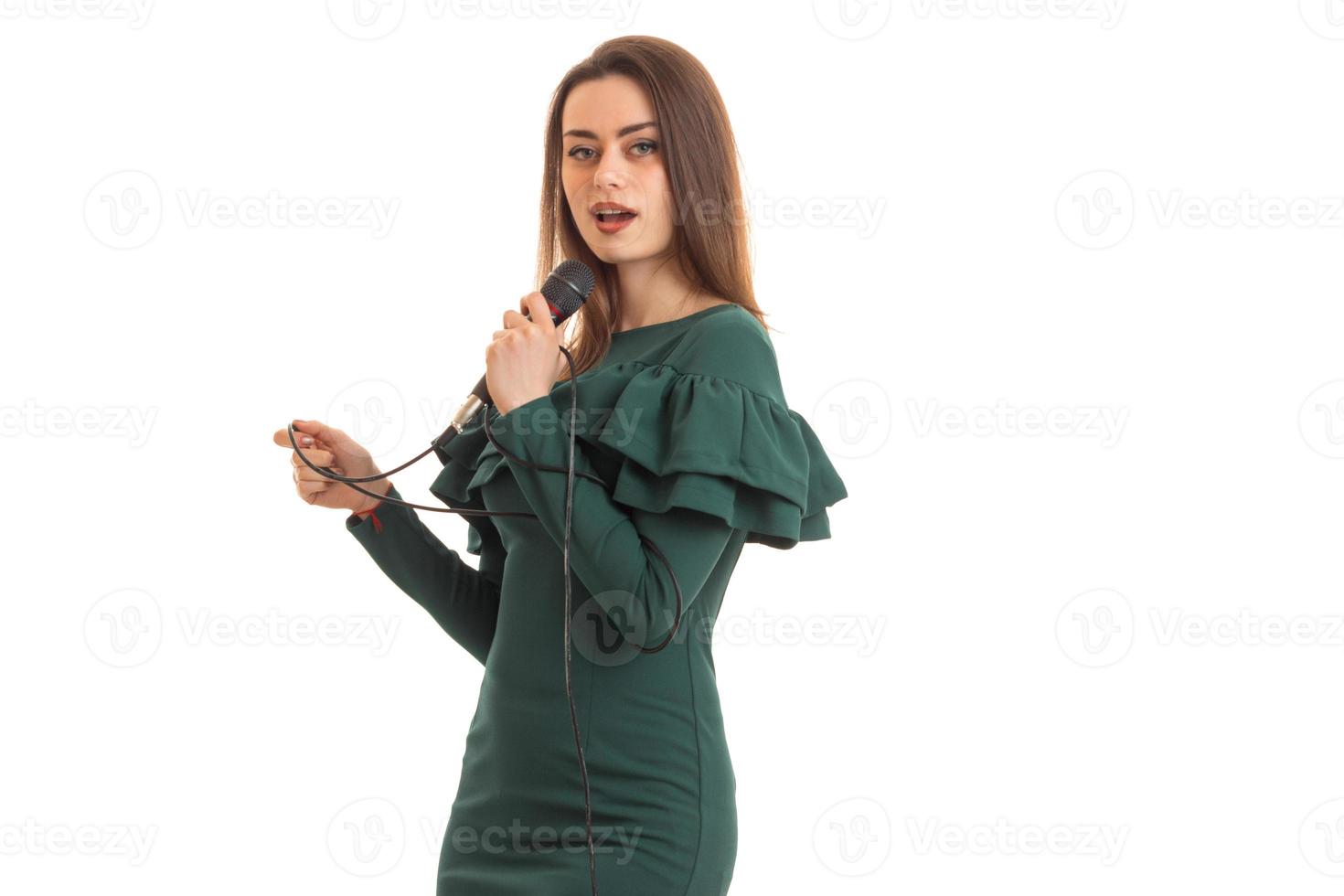 mooi jong meisje in een jurk het zingen in een microfoon foto