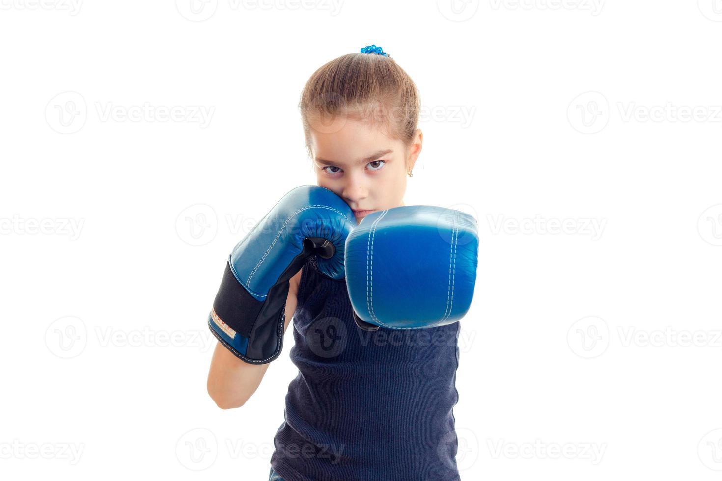 weinig echt meisje met boksen handschoenen staat in voorkant van de camera en trekt de handen foto