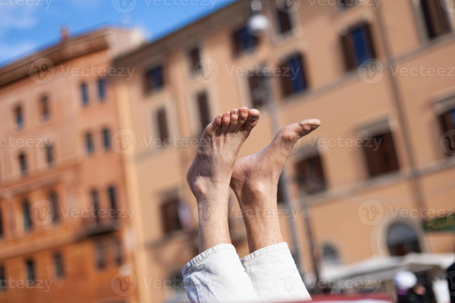 een Mens doet yoga en staat met zijn voeten omhoog Aan de straat. foto