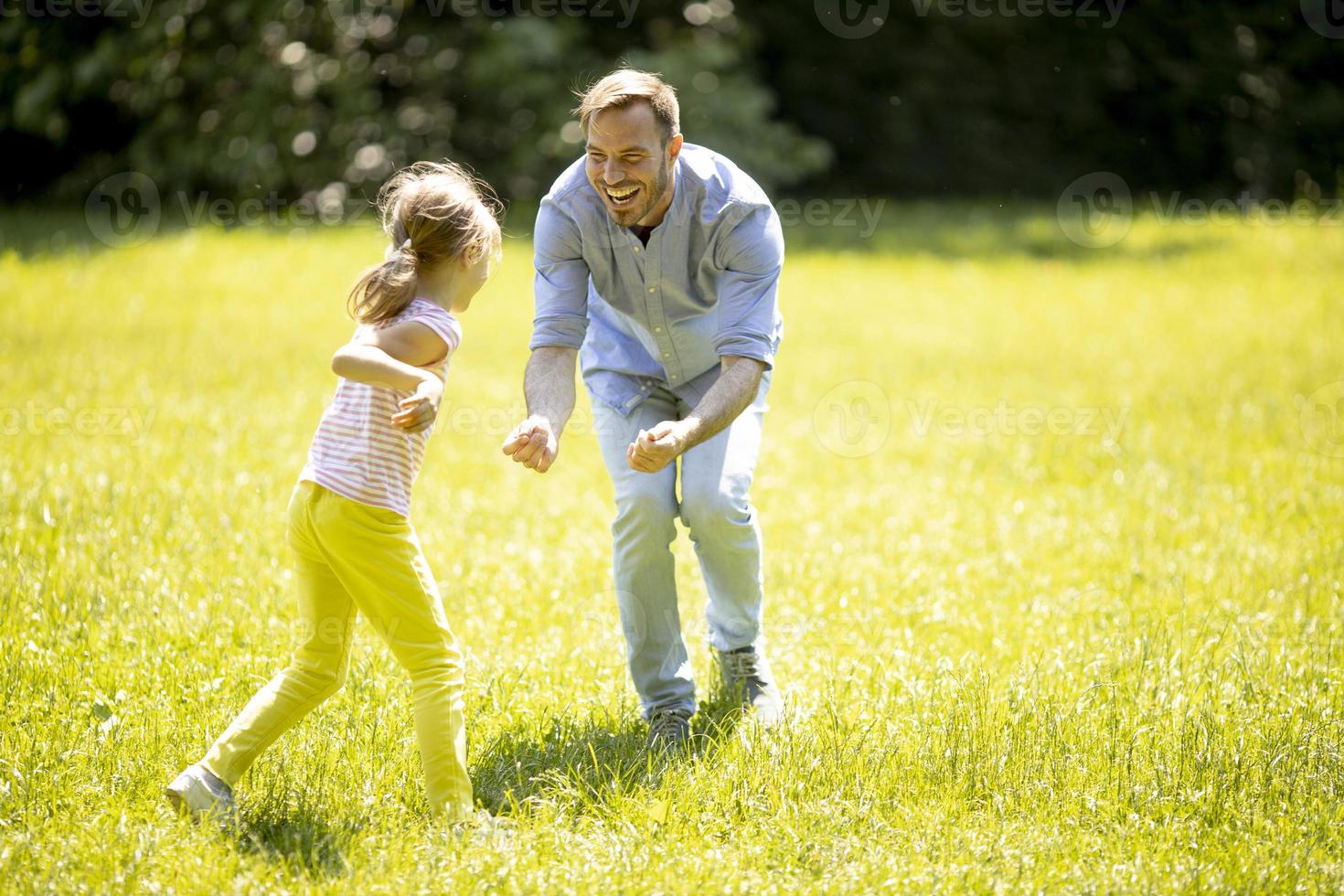vader die zijn dochtertje achtervolgt tijdens het spelen in het park foto