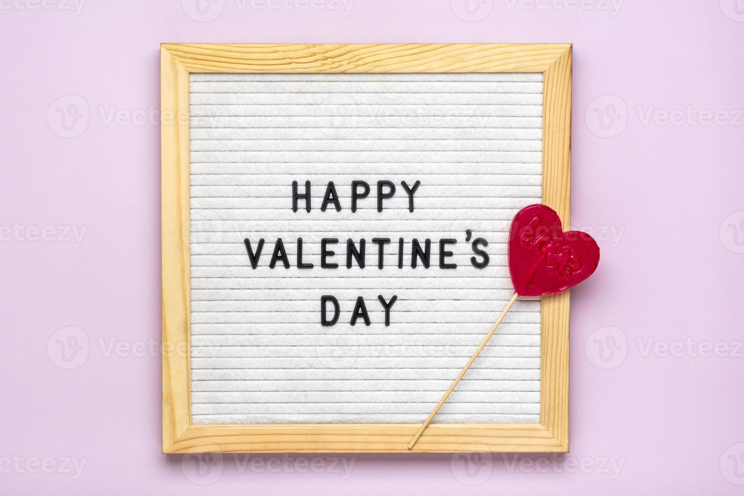 tekst gelukkig Valentijnsdag dag Aan voelde bord, rood snoepjes hart vormig Aan roze achtergrond top visie vlak leggen vakantie kaart, liefde concept foto