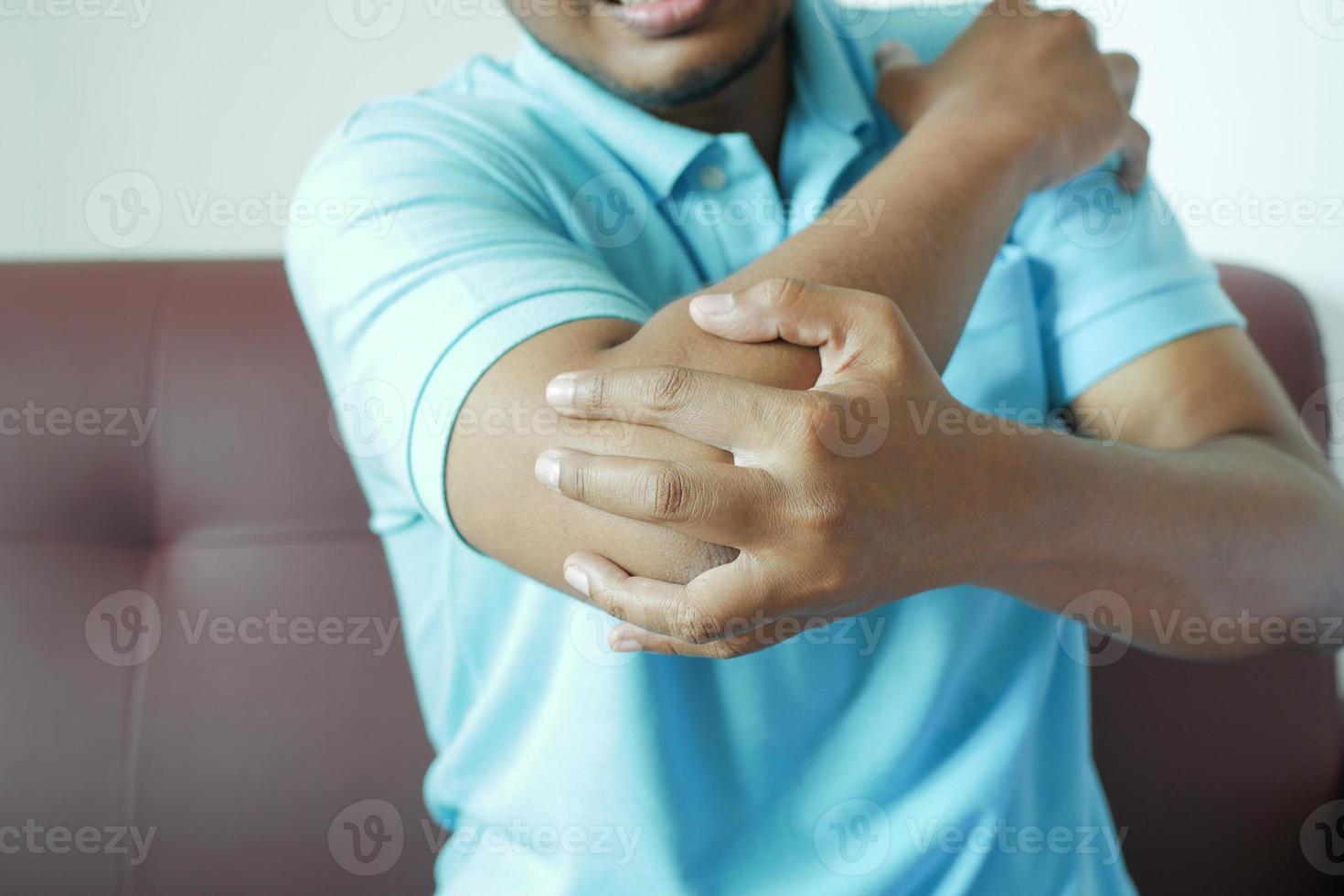 jonge man die pijn heeft aan de elleboog foto