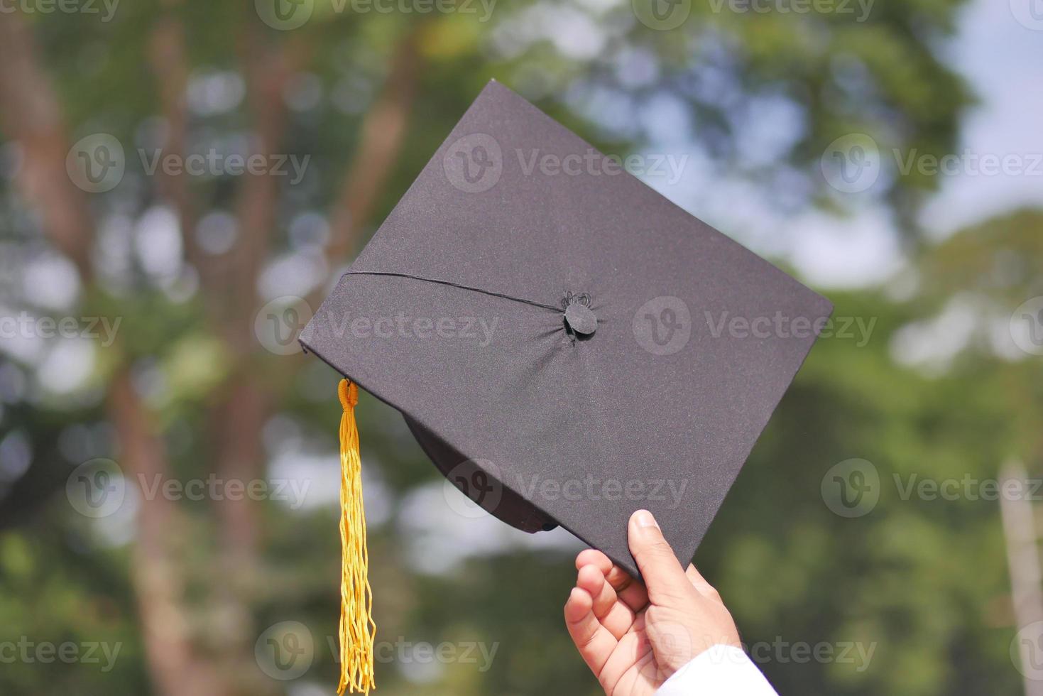 leerling houden hoeden in hand- gedurende aanvang succes Aan geel achtergrond foto