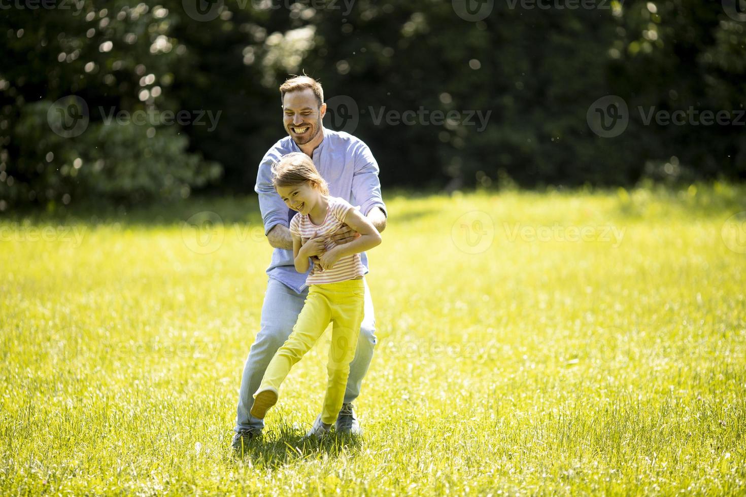 vader die zijn dochtertje achtervolgt tijdens het spelen in het park foto