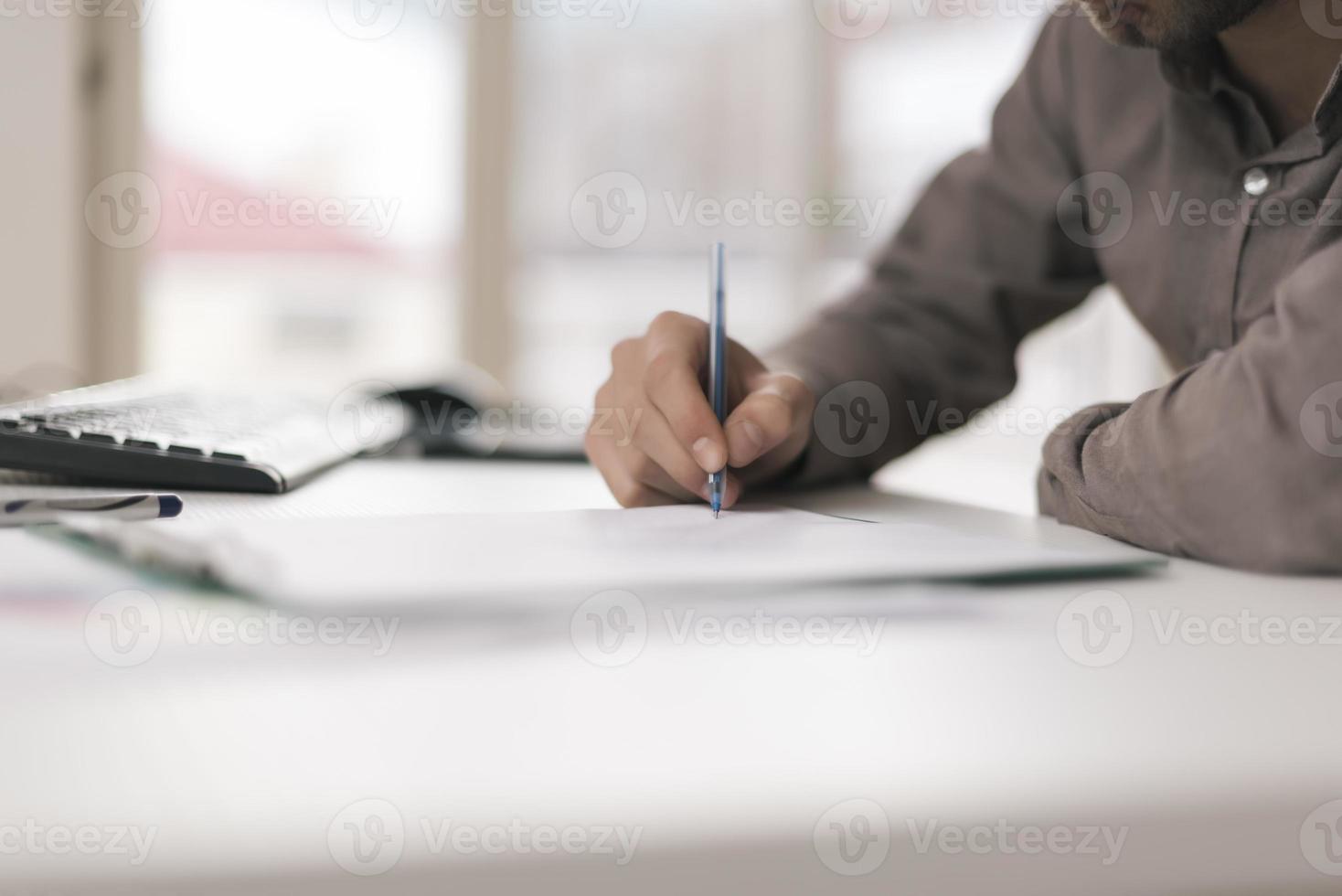 portret van jong Mens zittend Bij zijn bureau in de kantoor werken Aan is laptop foto