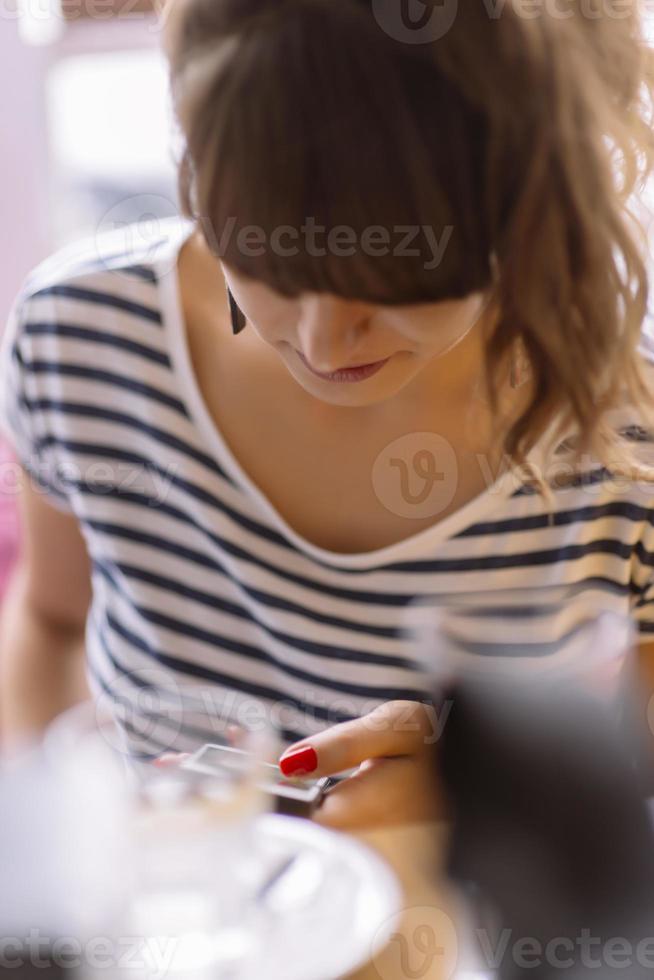 meisje sms'en Aan de slim telefoon in een restaurant terras met een ongericht achtergrond foto