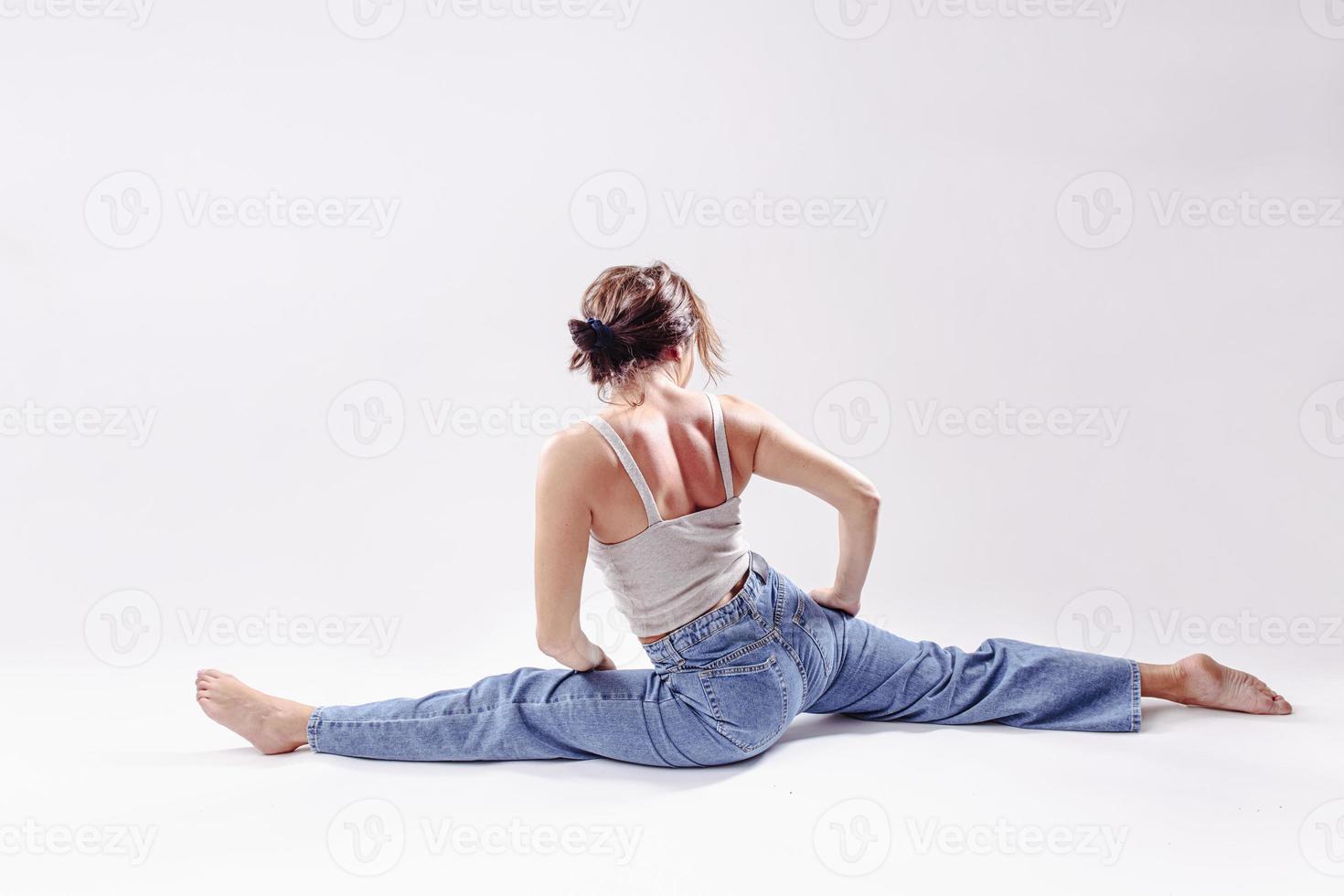 portret van mooi jong vrouw met atletisch flexibel lichaam aan het doen been uitrekken. geïsoleerd foto