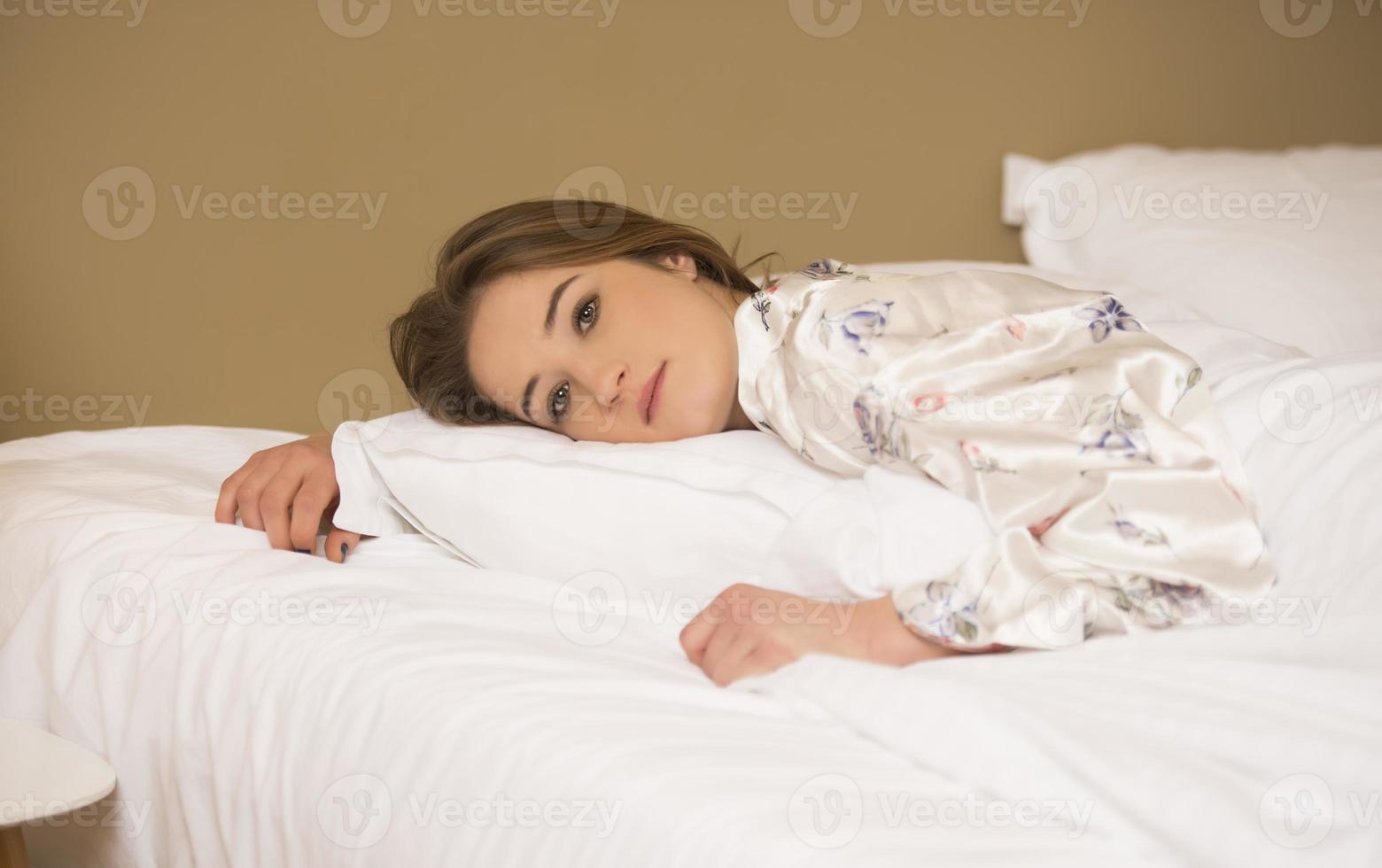 vredig sereen mooi jong dame slijtage pyjama aan het liegen in slaap ontspannende slapen in knus wit bed Aan zacht hoofdkussen resting foto
