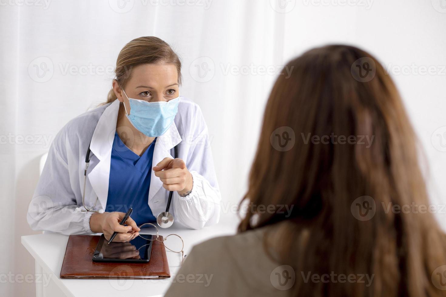 jong brunette vrouw hebben overleg Bij dokter kantoor gedurende coronavirus en griep uitbraak. vrouw dokter vervelend gezichtsmasker. virus bescherming. covid 19. foto