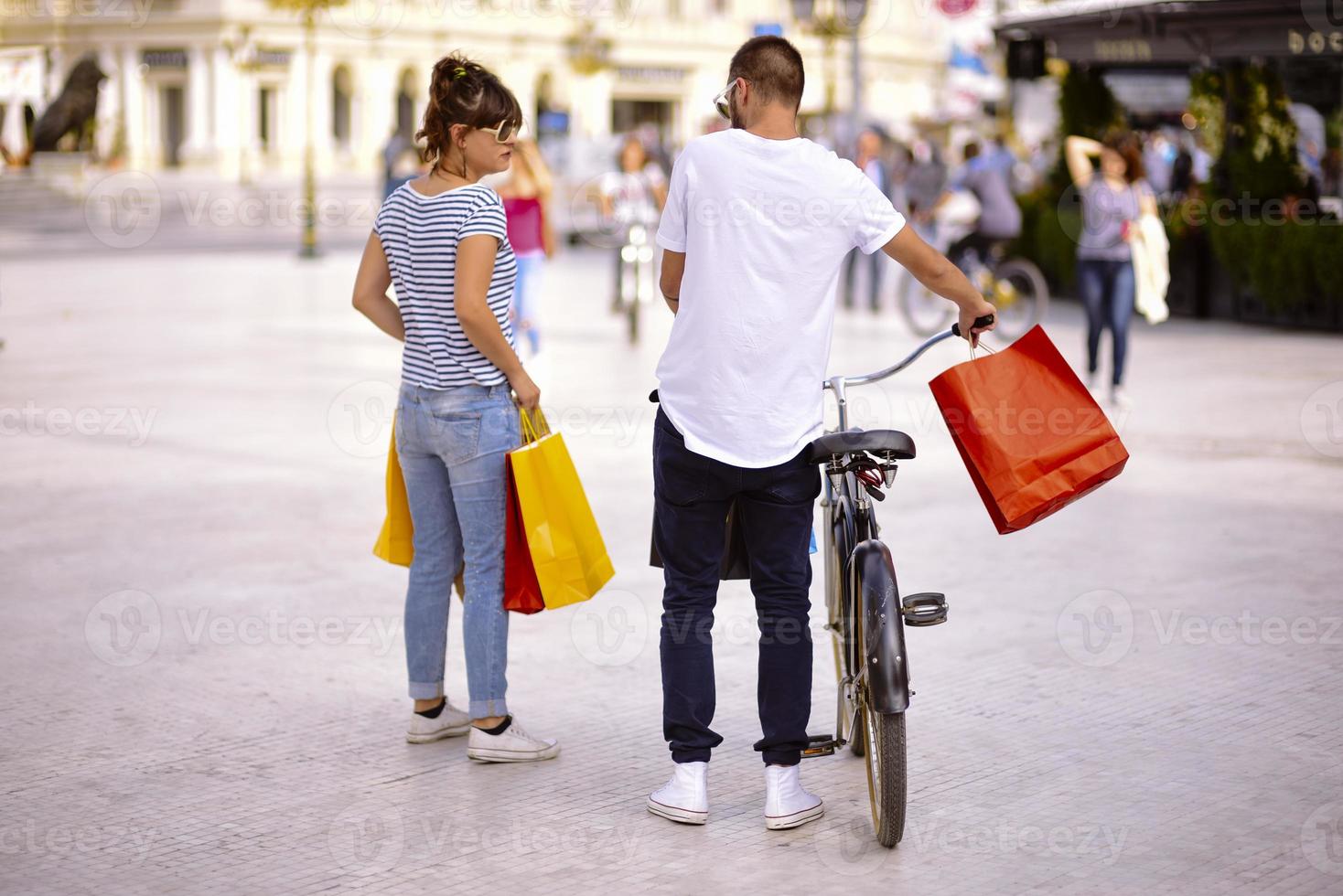 portret van vrolijk Kaukasisch jong paar Mens en vrouw Holding veel papier Tassen na boodschappen doen terwijl wandelen en pratend Aan straat. gelukkig familie paar met pakketjes buitenshuis. buying concept foto