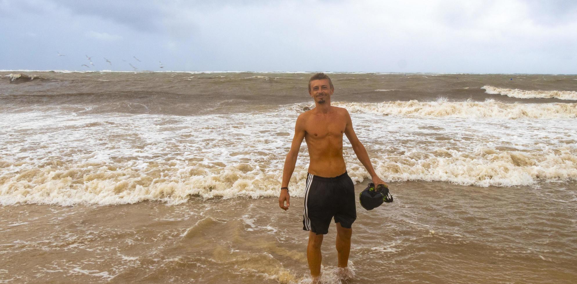 Mens is uit Aan strand gedurende orkaan en geniet Mexico. foto