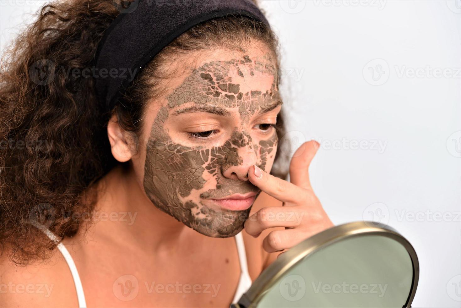 mooi vrouw Verwijderen klei gelaats masker van haar gezicht foto