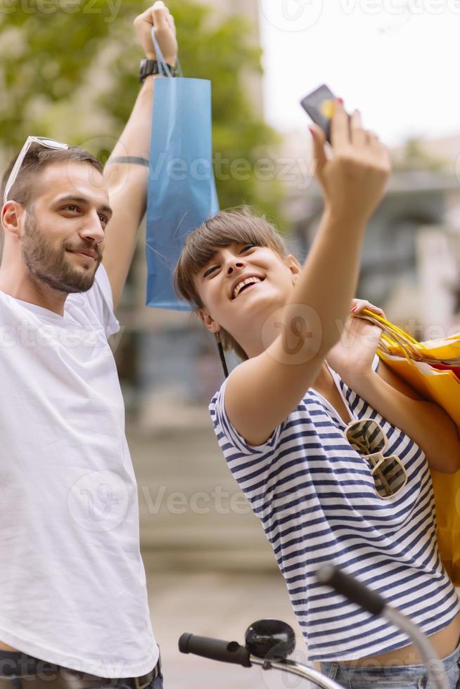 portret van vrolijk Kaukasisch jong paar Mens en vrouw Holding veel papier Tassen na boodschappen doen terwijl wandelen en pratend Aan straat. gelukkig familie paar met pakketjes buitenshuis. buying concept foto