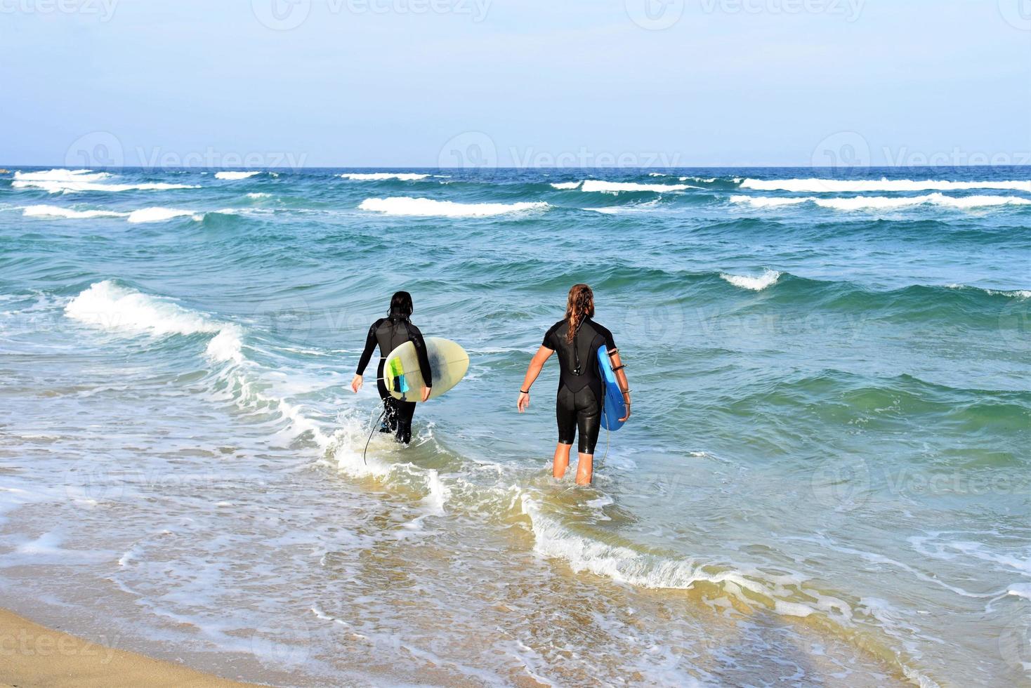 surfers paar aan het wachten voor de hoog golven Aan strand - sportief mensen met surfen borden Aan de strand - extreem sport en vakantie concept foto