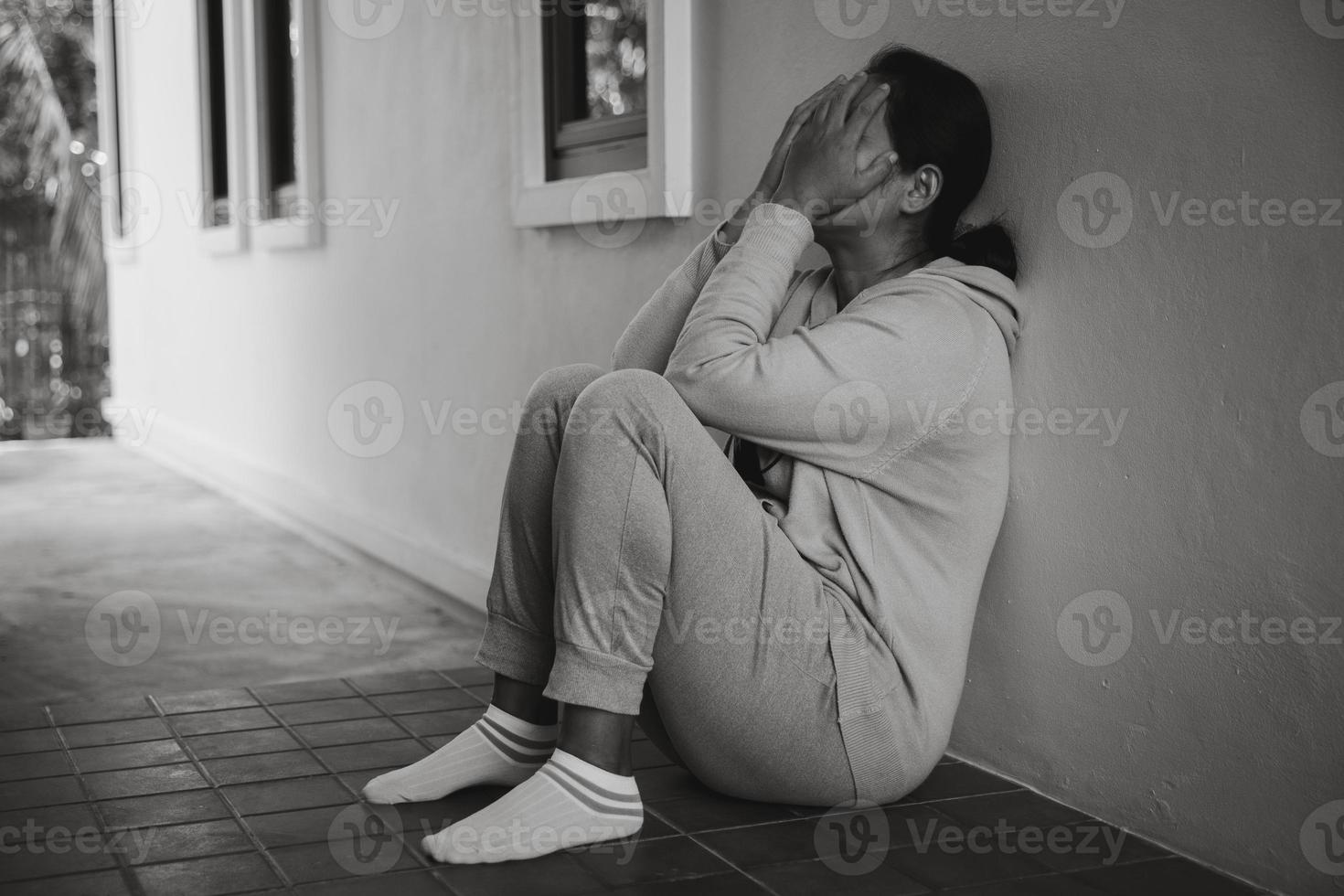 schizofrenie met eenzaam en verdrietig in mentaal Gezondheid depressie concept. depressief vrouw zittend tegen verdieping Bij huis met donker kamer gevoel miserabel. Dames zijn depressief, angstig en ongelukkig. foto