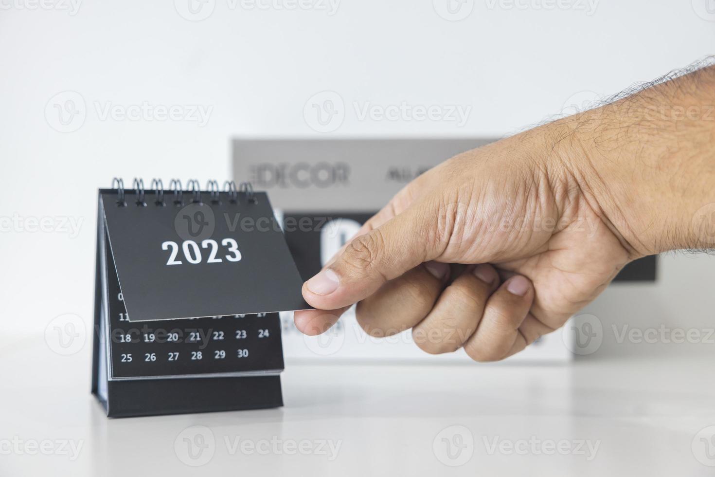 hand- Holding 2023 bedrijf kalender Aan kantoor tafel in nieuw jaar dag. maken een werk plan voor de begin van de jaar. concept over viering, bedrijf, kerstmis, nieuw jaar. foto