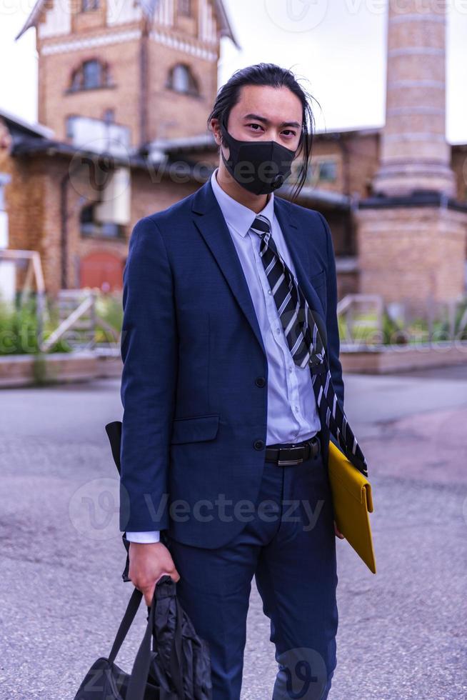 knap Aziatisch zakenman vervelend covid masker en pak, wandelen buitenshuis, geslaagd manager gedurende breken wandelen in de stad. foto