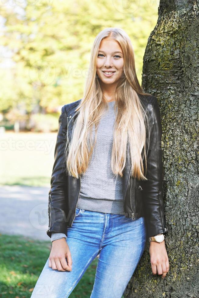 jong vrouw leunend tegen boom in park foto