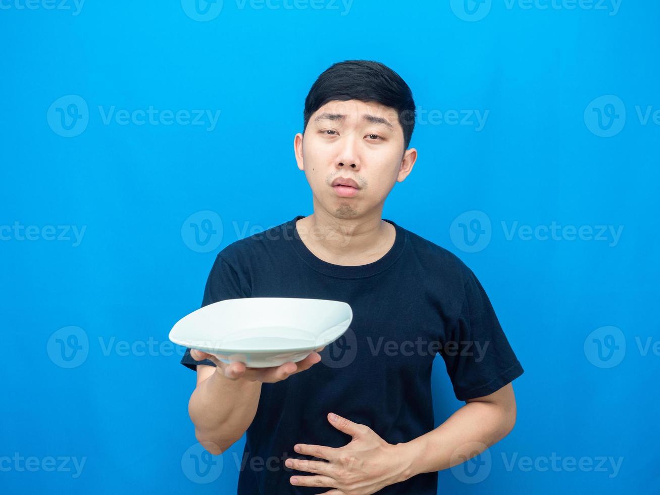 Mens Holding schotel en tintje buik gevoel hongerig blauw achtergrond foto