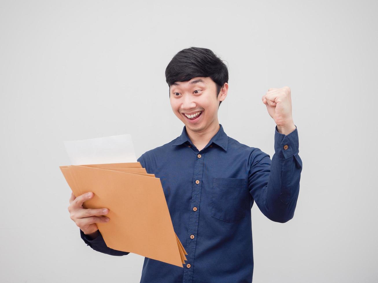 Aziatisch Mens lezing Bij document envelop in hand- gevoel gelukkig en glimlach tonen vuist omhoog wit achtergrond foto