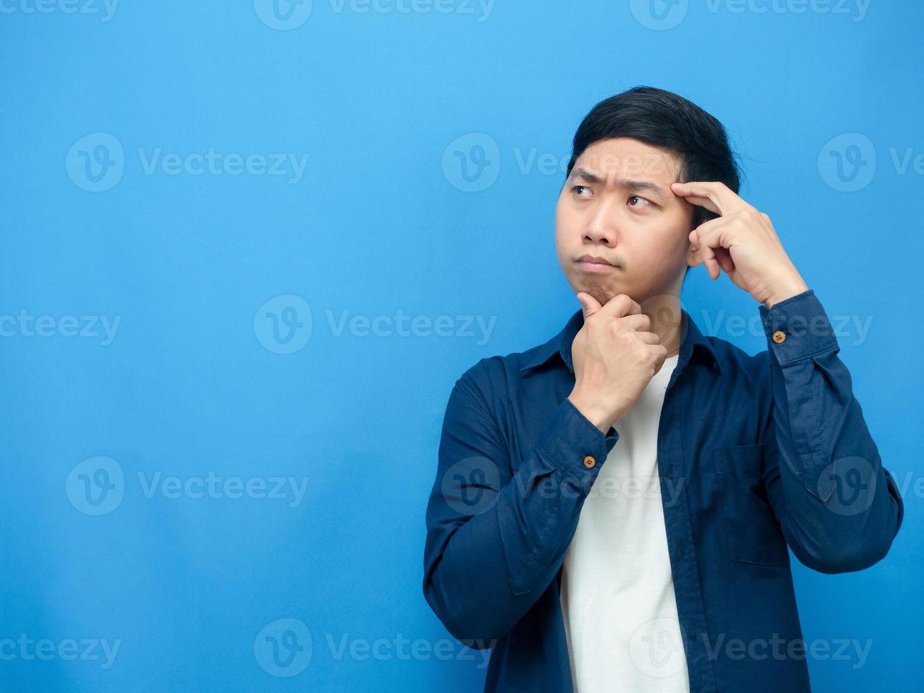 Aziatisch Mens gebaar denken ongeveer iets op zoek Bij kopiëren ruimte blauw achtergrond foto