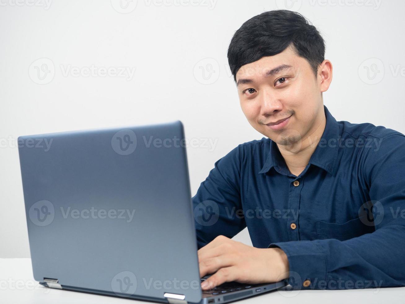 mannetje werknemer gebruik makend van laptop voor werk en op zoek Bij camera en glimlachen foto