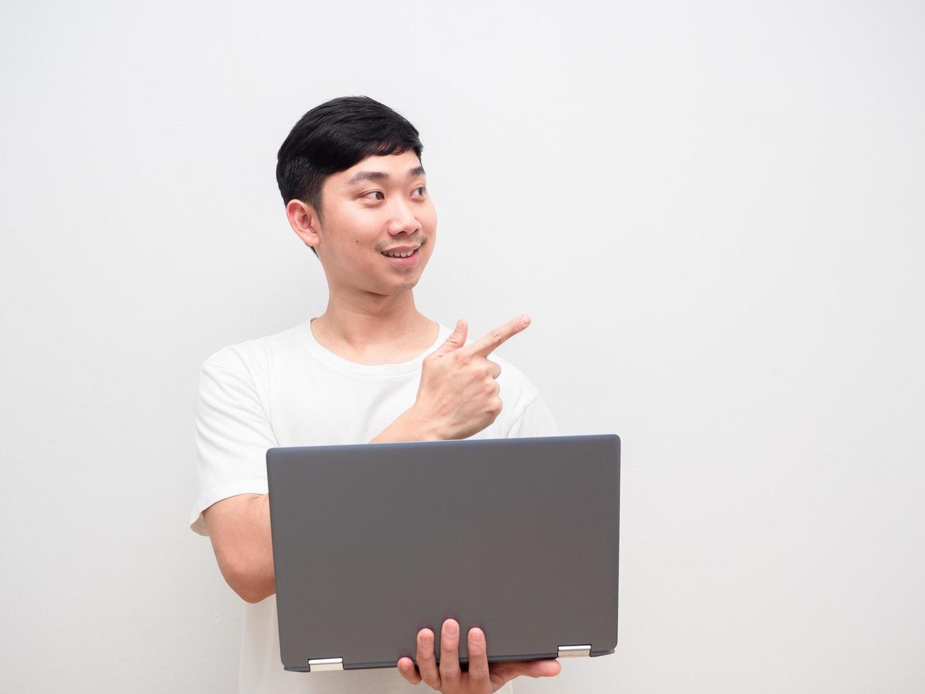 Aziatisch Mens vrolijk Holding laptop punt vinger Bij ruimte wit achtergrond foto