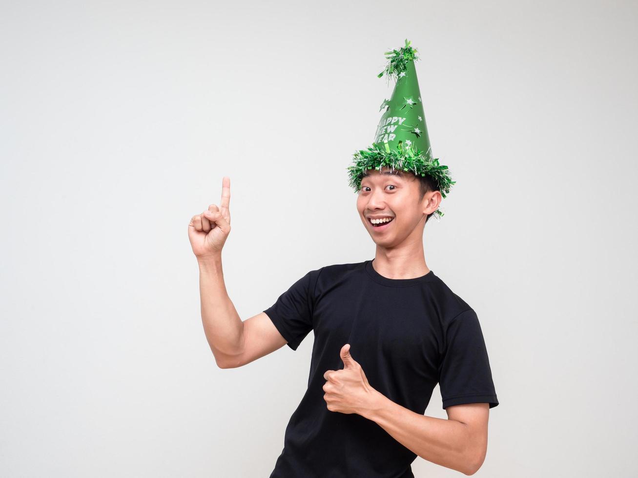 jong Aziatisch Mens gelukkig gezicht kijken Bij camera met groen hoed punt Rechtsaf vinger bovenstaand duim omhoog en gelukkig glimlach Aan wit geïsoleerd achtergrond foto