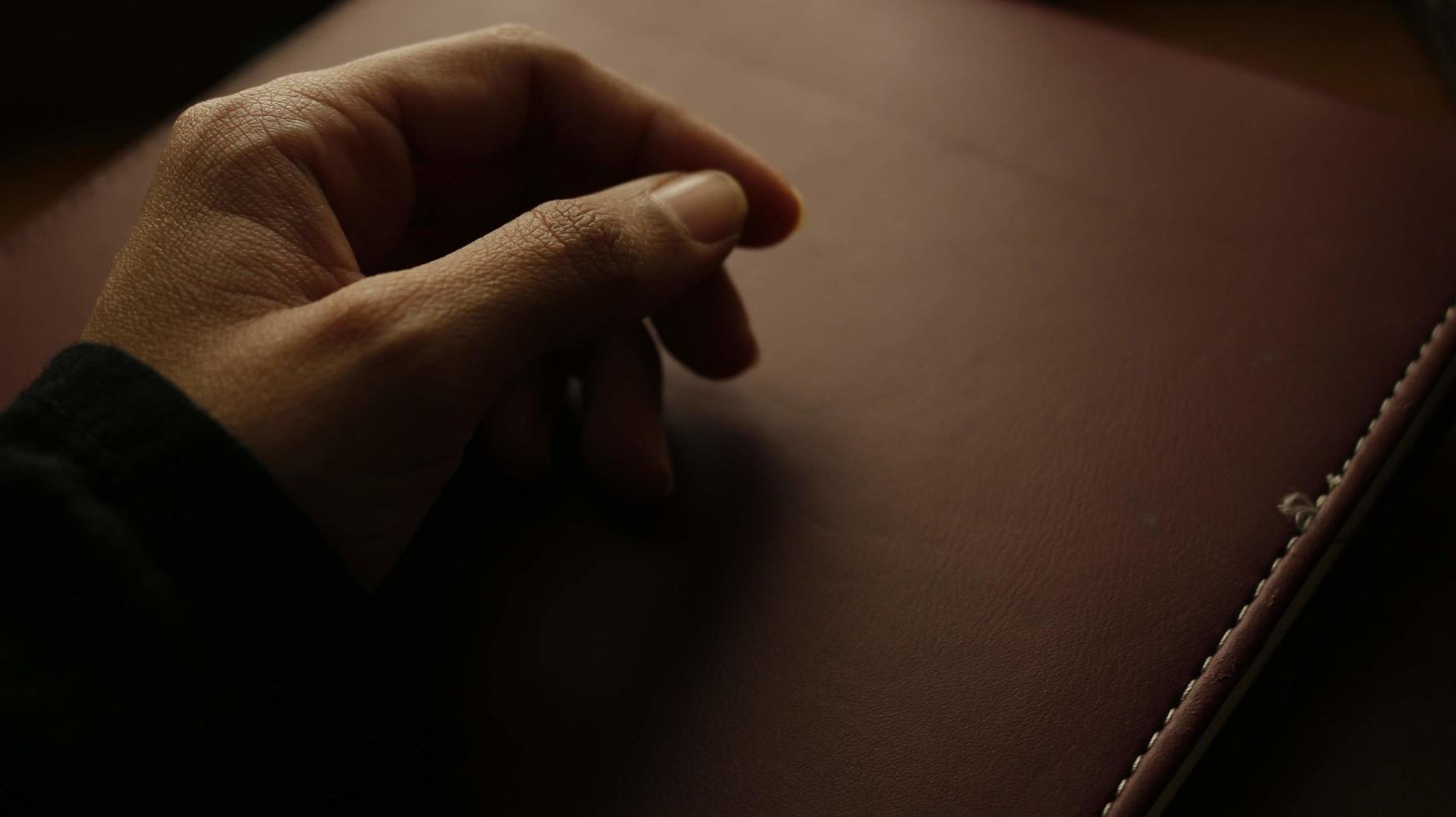 detailopname van een vrouw hand- Aan een boek in een somber instelling foto