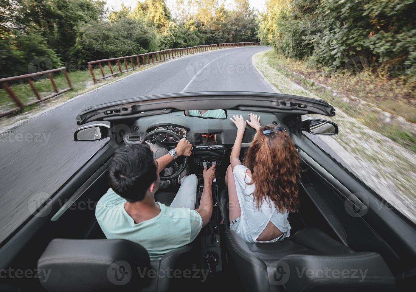 vrienden hebben pret Bij auto reis in de omgeving van de wereld. paar in liefde met armen omhoog Aan een converteerbaar auto. foto