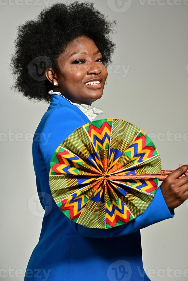 mooi Afrikaanse Amerikaans vrouw met modieus accessoires en afro kapsel op zoek Bij camera tegen grijs achtergrond foto