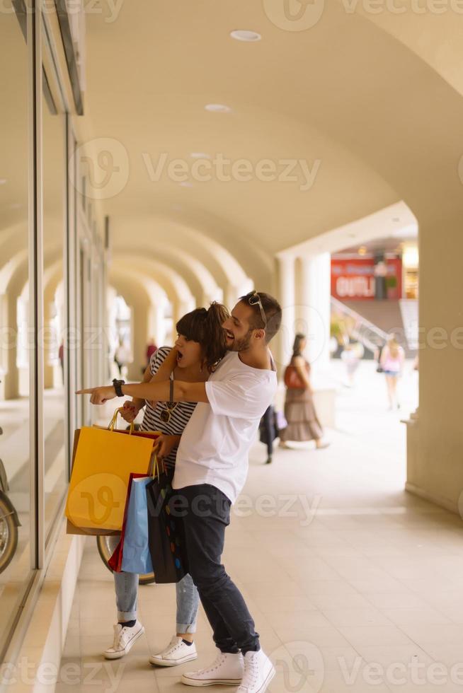 portret van vrolijk Kaukasisch jong paar Mens en vrouw Holding veel papier Tassen na boodschappen doen terwijl wandelen en pratend Aan straat. gelukkig familie paar met pakketjes buitenshuis. buying concept foto