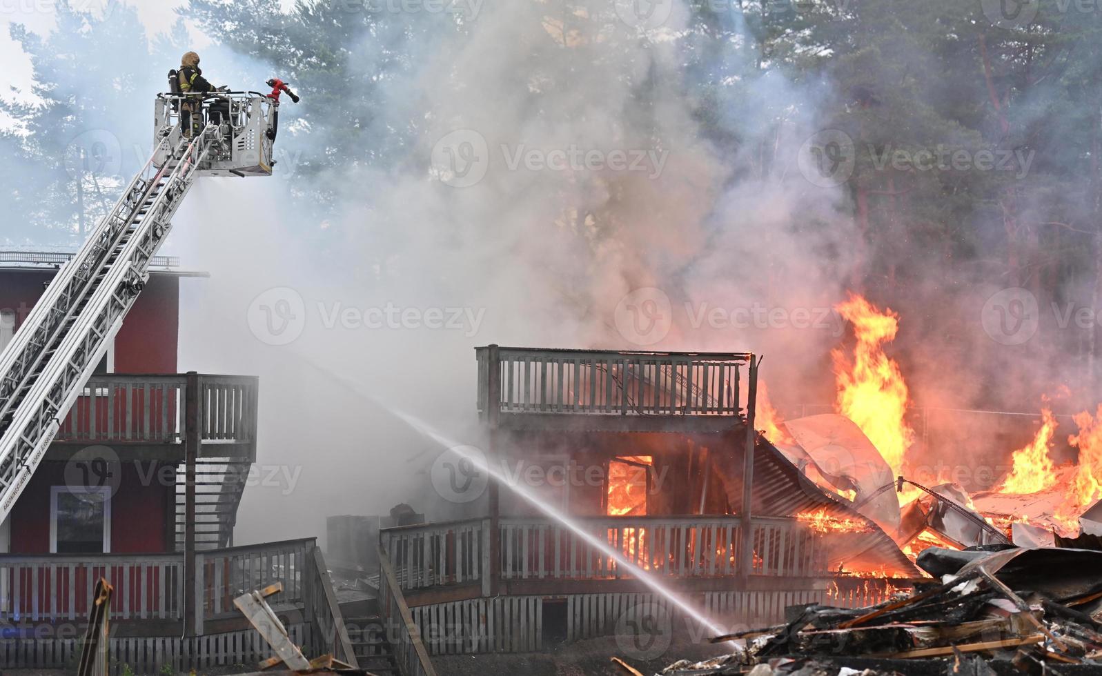 single brand vechter sprays een Rechtdoor stoom- in een ten volle betrokken gebouw brand foto