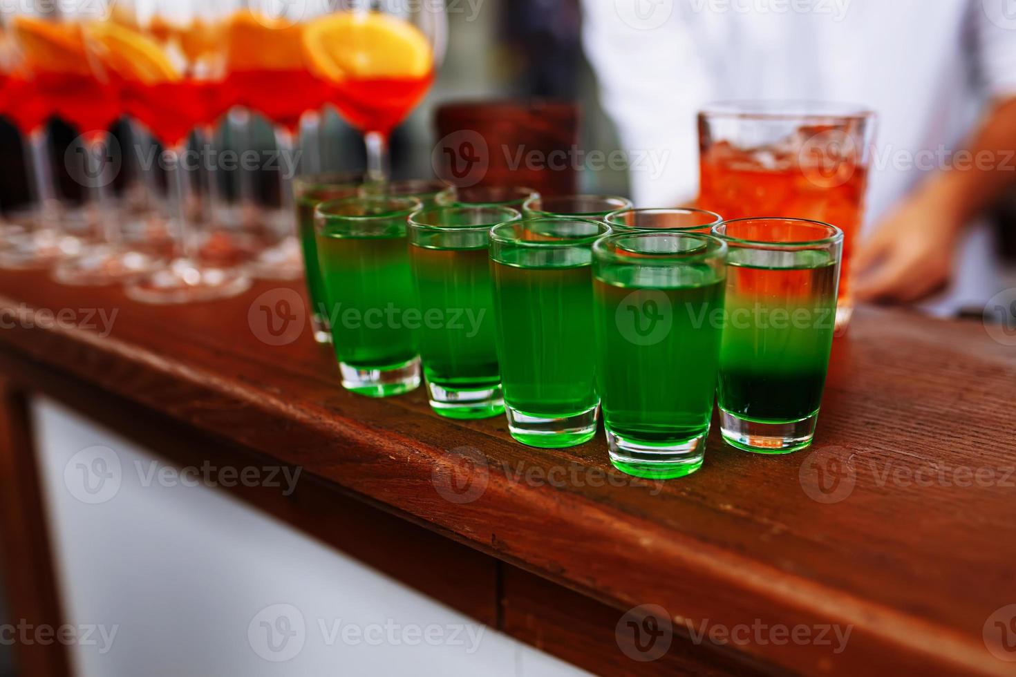 drankjes voor st. Patrick dag feest. mooi zo geluk elf van Ierse folklore schot cocktail. groen sterk drinken in een schot glas. bril van aperol spritz en schoten of schutters Aan houten bar teller in een restaurant, kroeg. foto