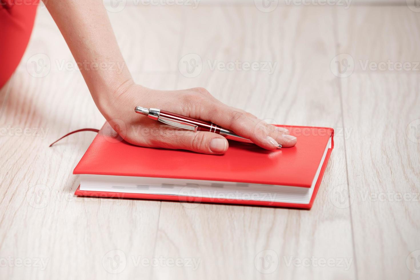 detailopname van een jong vrouw hand- met een pen en notitieboekje voor schrijven plan van de dag. de concept van werken en aan het studeren Bij huis. foto