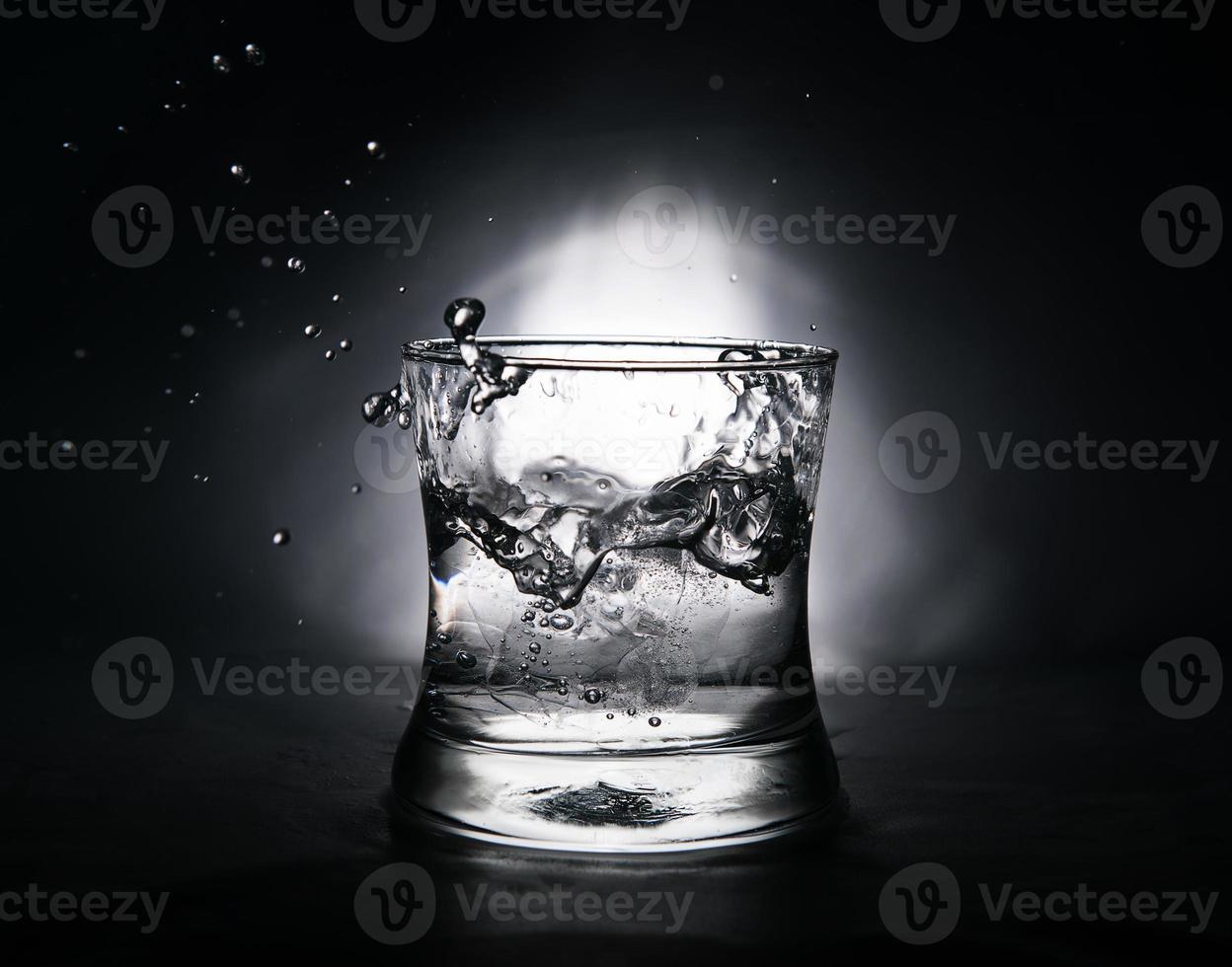 ijs kubus spatten in een glas vol van water foto