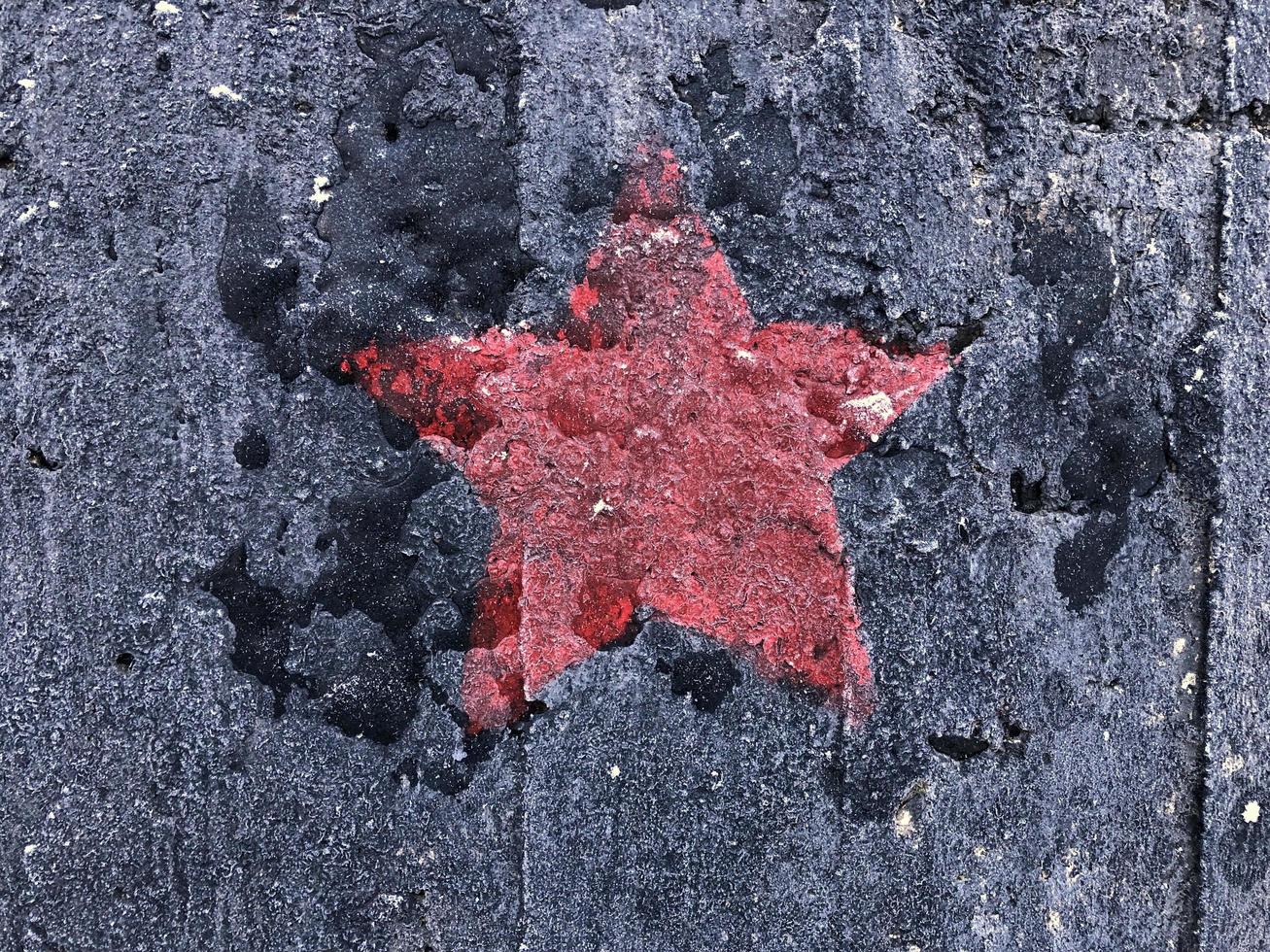 rood vijfpuntig ster Aan een zwart haveloos achtergrond foto