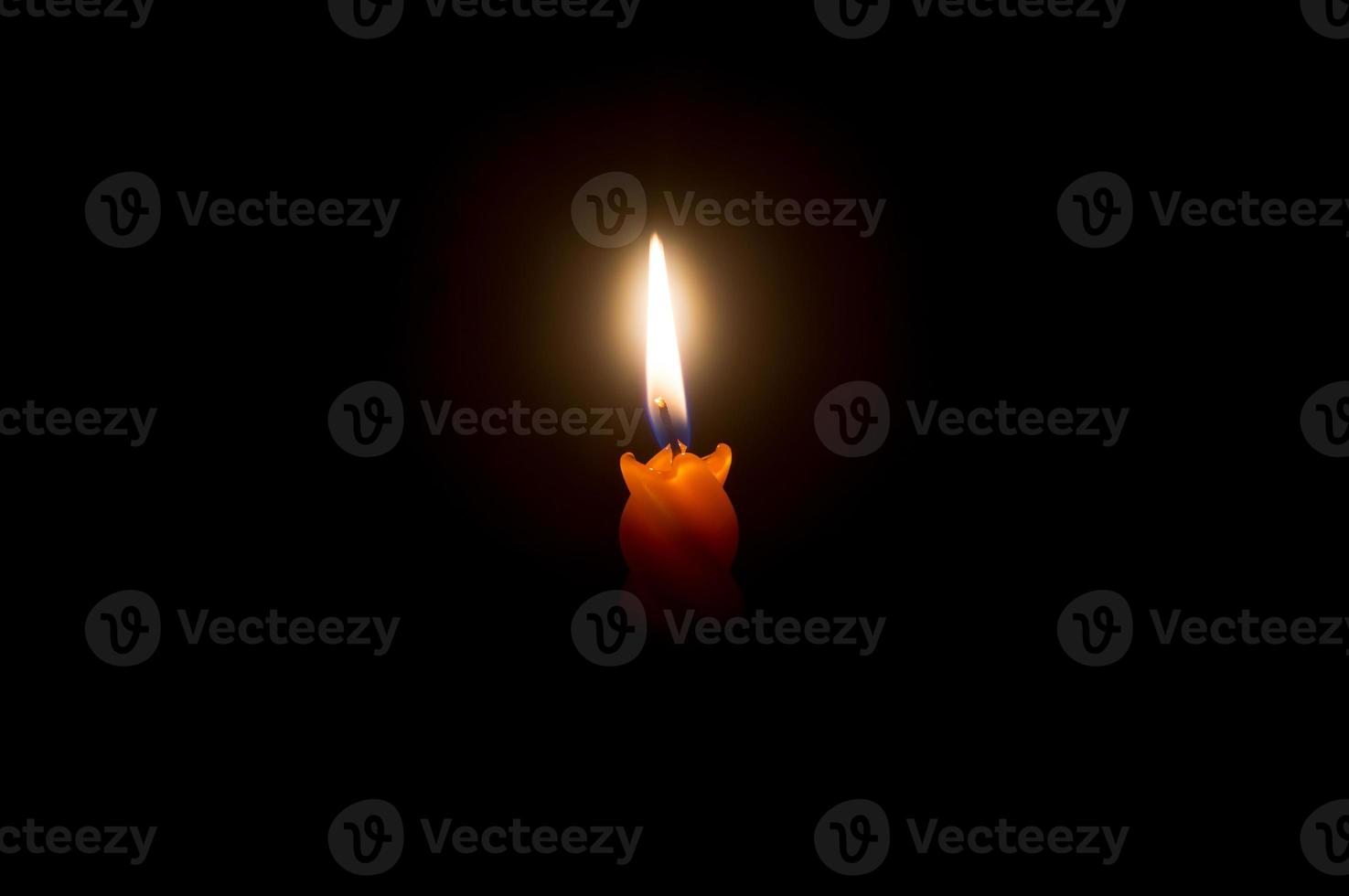 een single brandend kaars vlam of licht gloeiend Aan een oranje spiraal kaars Aan zwart of donker achtergrond Aan tafel in kerk voor kerstmis, begrafenis of gedenkteken onderhoud met kopiëren ruimte foto