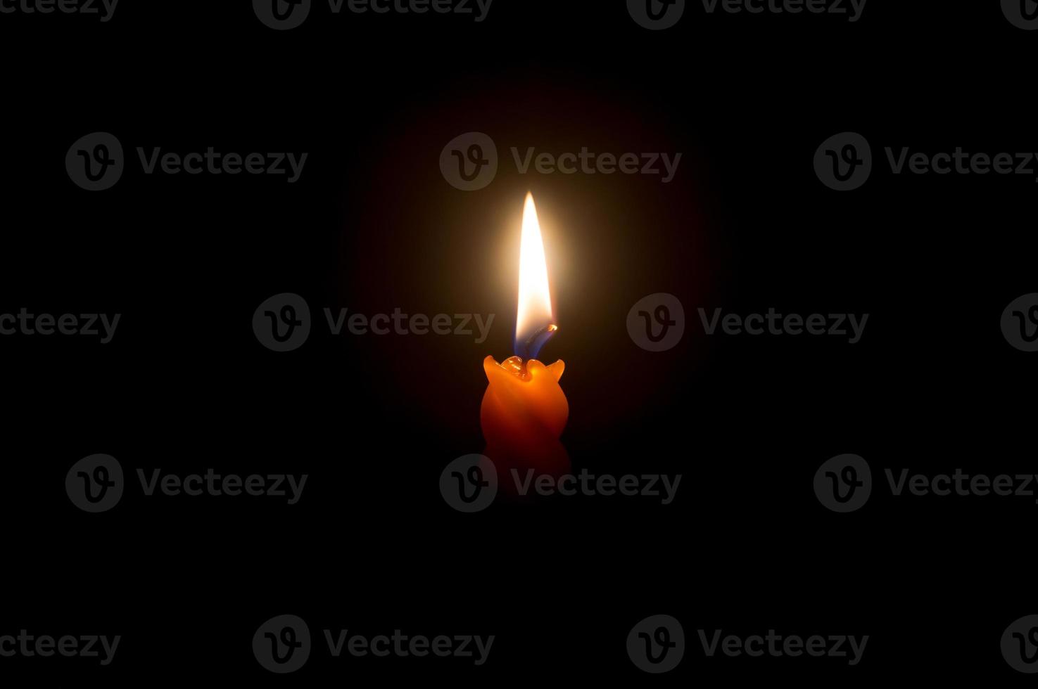 een single brandend kaars vlam of licht gloeiend Aan een mooi spiraal oranje kaars Aan zwart of donker achtergrond Aan tafel in kerk voor kerstmis, begrafenis of gedenkteken onderhoud foto