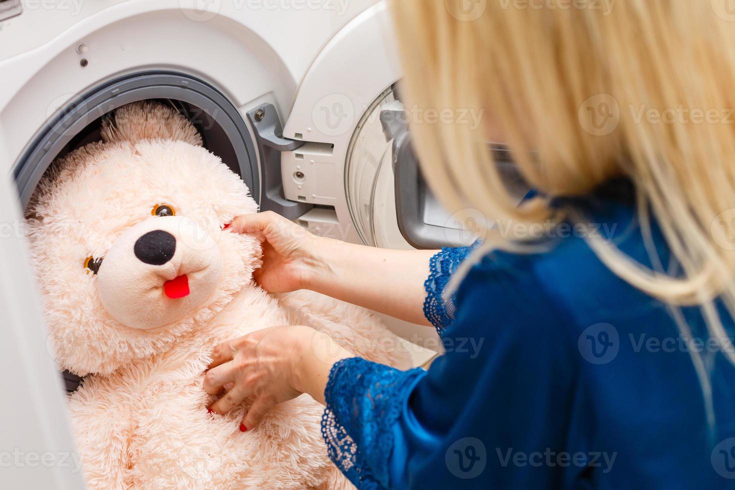 vrouw bezig met laden pluizig speelgoed- in de het wassen machine foto